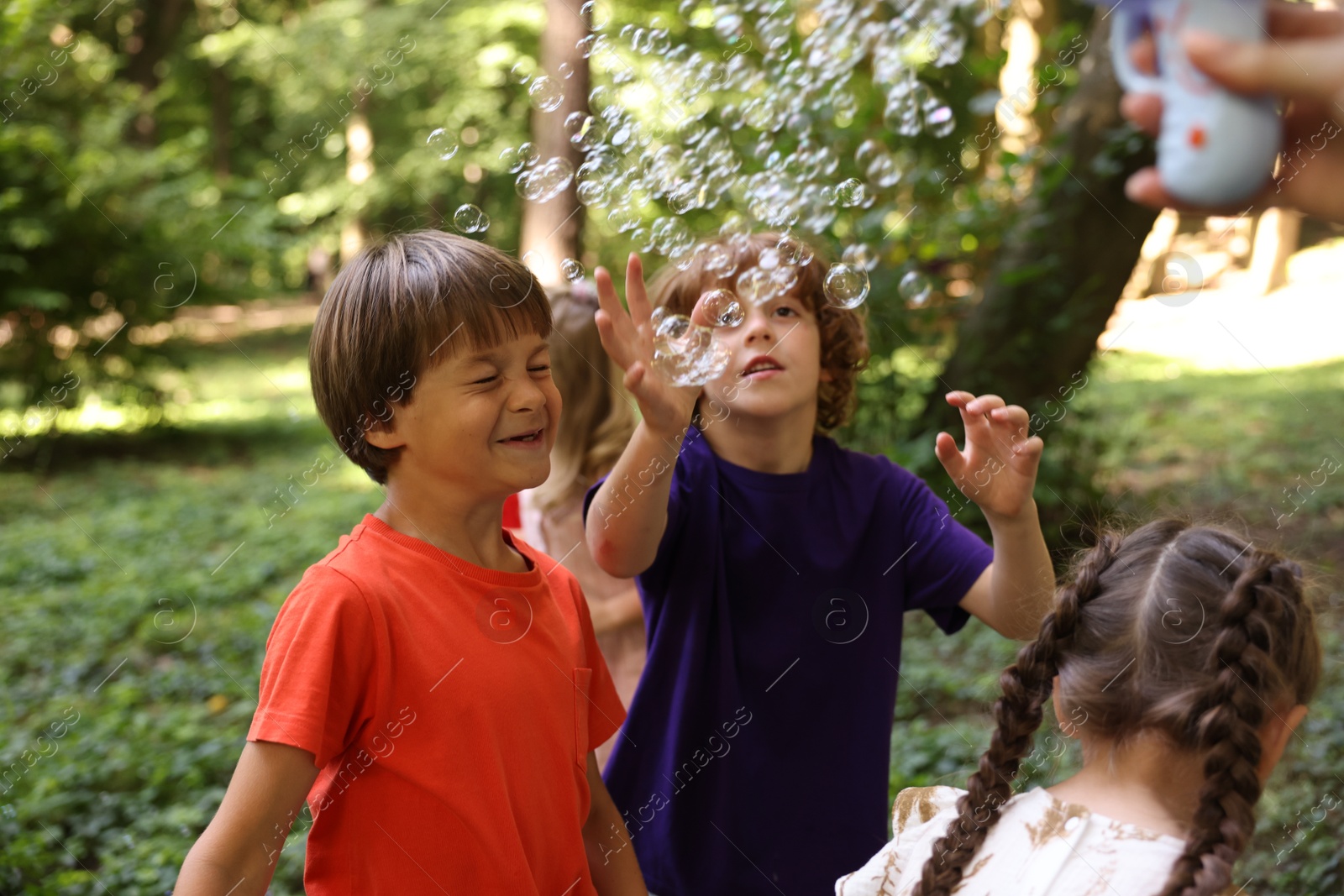Photo of Cute little kids having fun with soap bubbles in park