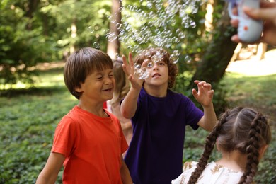 Photo of Cute little kids having fun with soap bubbles in park