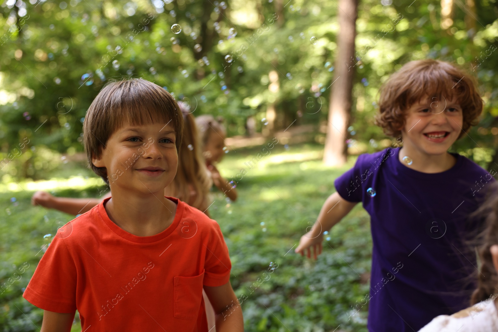 Photo of Cute little kids having fun with soap bubbles in park