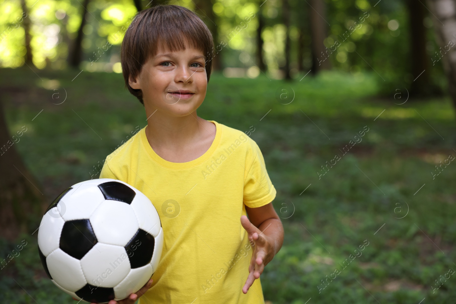 Photo of Cute little boy with soccer ball in park, space for text