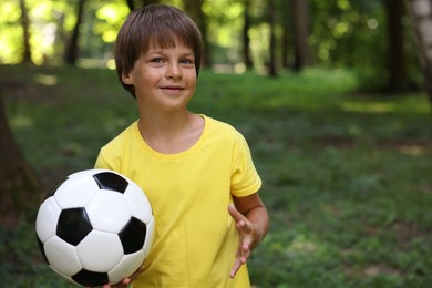 Photo of Cute little boy with soccer ball in park, space for text