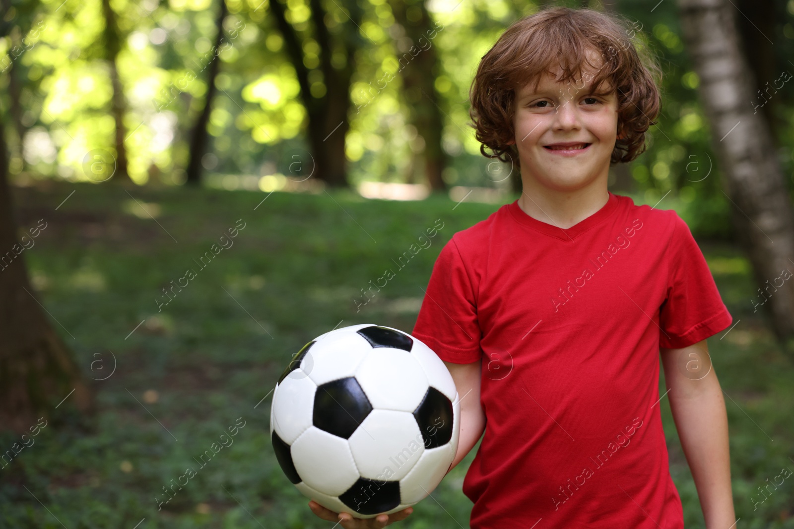 Photo of Cute little boy with soccer ball in park, space for text
