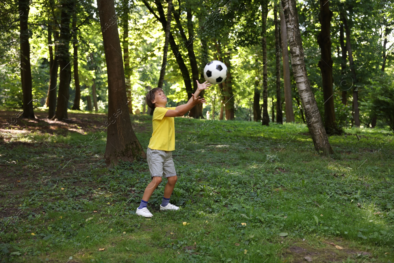 Photo of Cute little boy playing with soccer ball in park