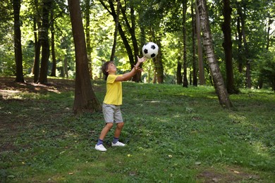 Photo of Cute little boy playing with soccer ball in park