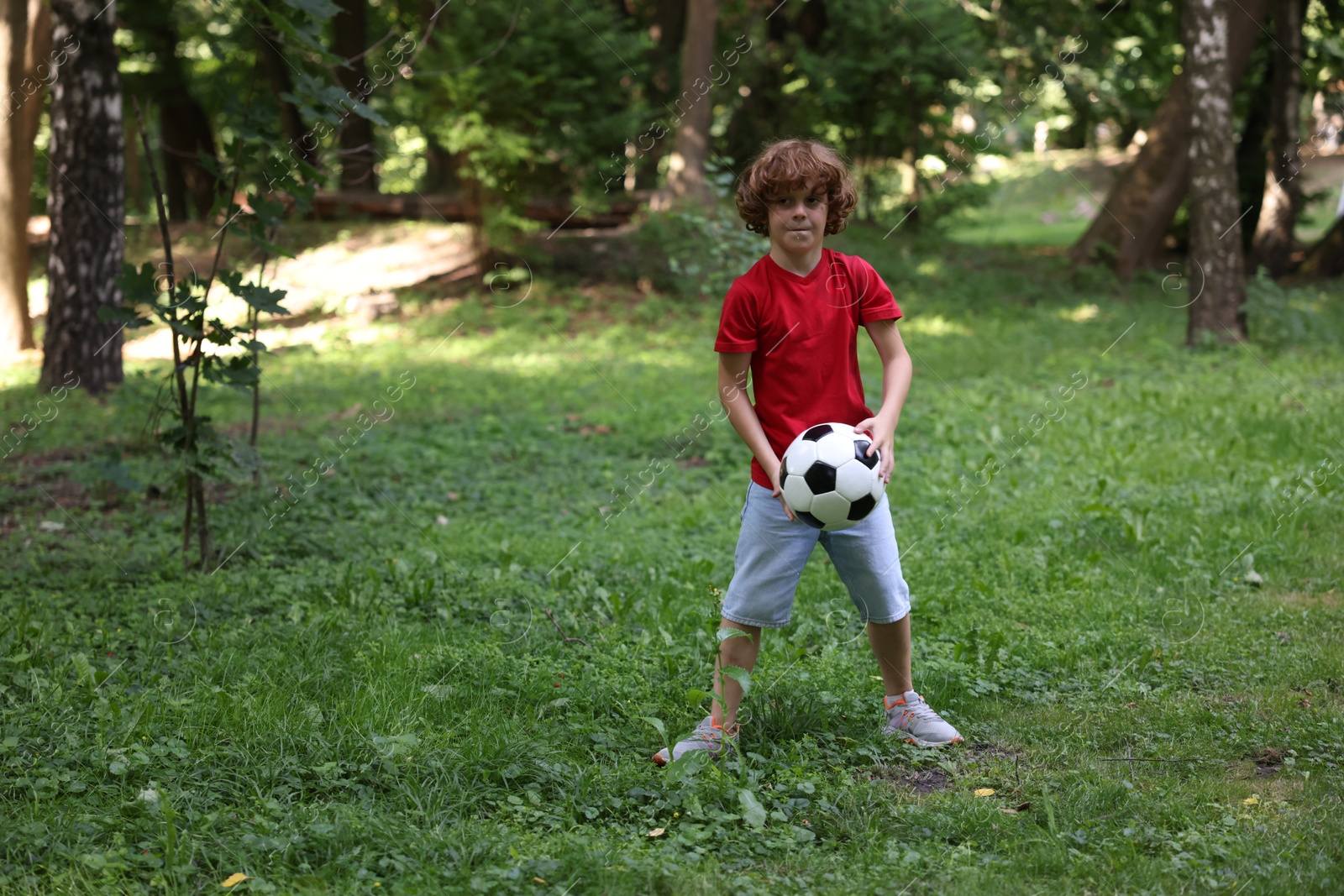 Photo of Cute little boy playing with soccer ball in park, space for text