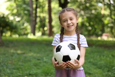 Photo of Cute little girl with soccer ball in park, space for text