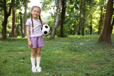 Photo of Cute little girl with soccer ball in park, space for text