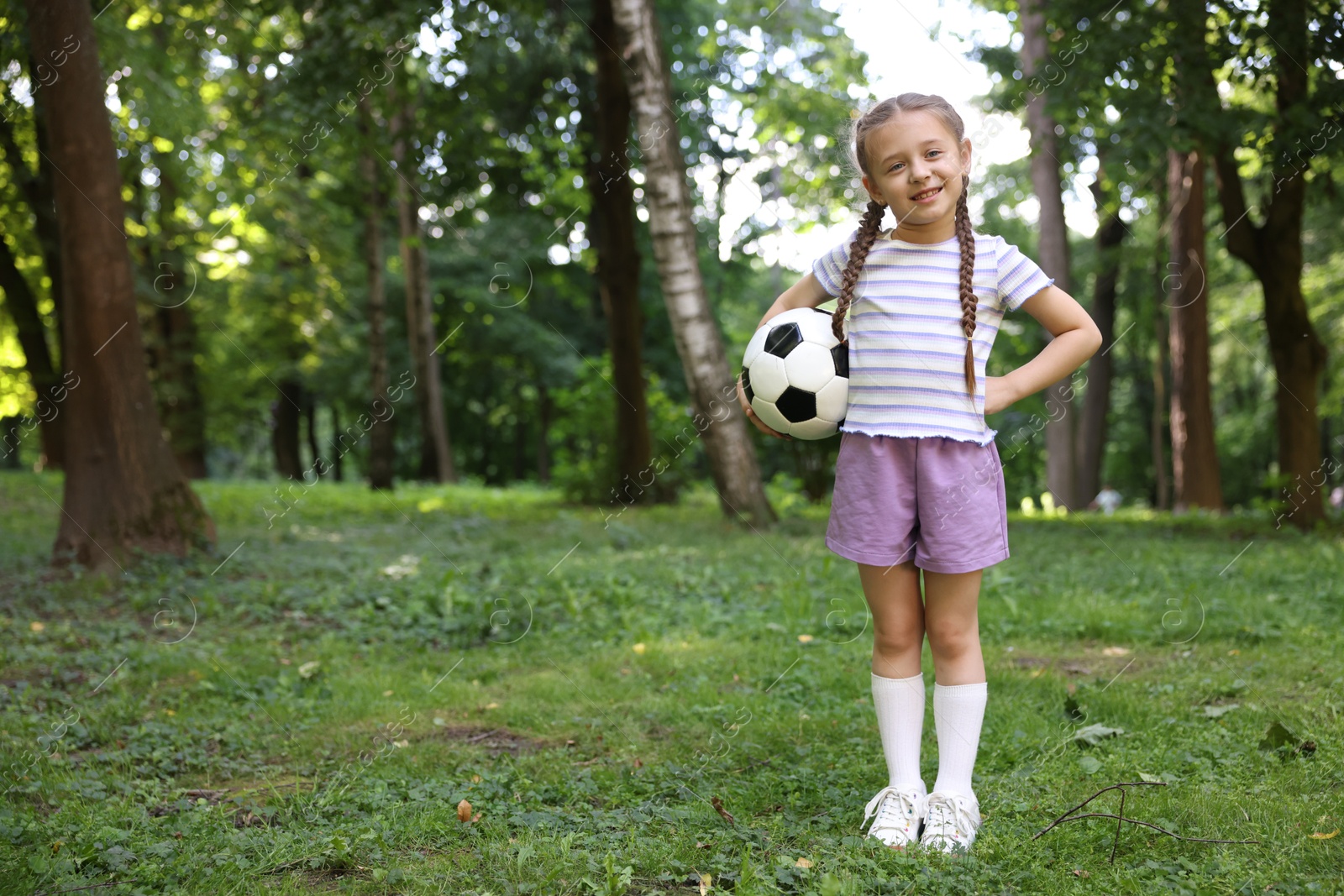 Photo of Cute little girl with soccer ball in park, space for text