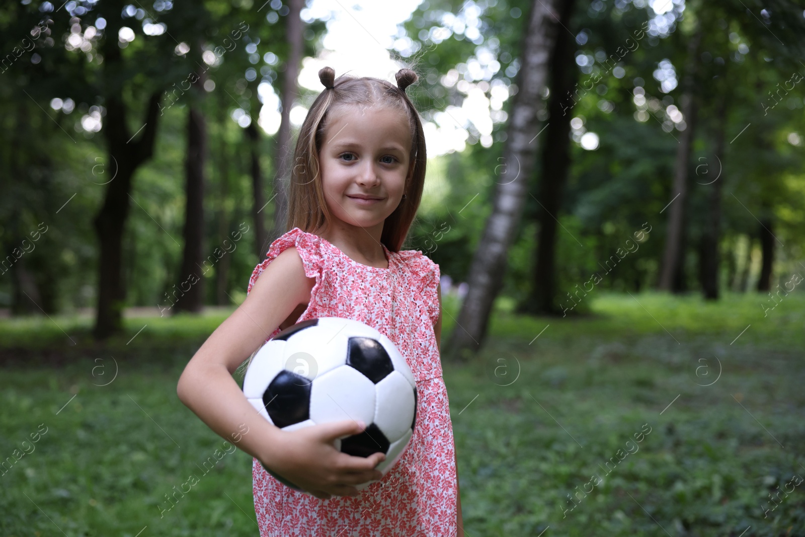 Photo of Cute little girl with soccer ball in park, space for text