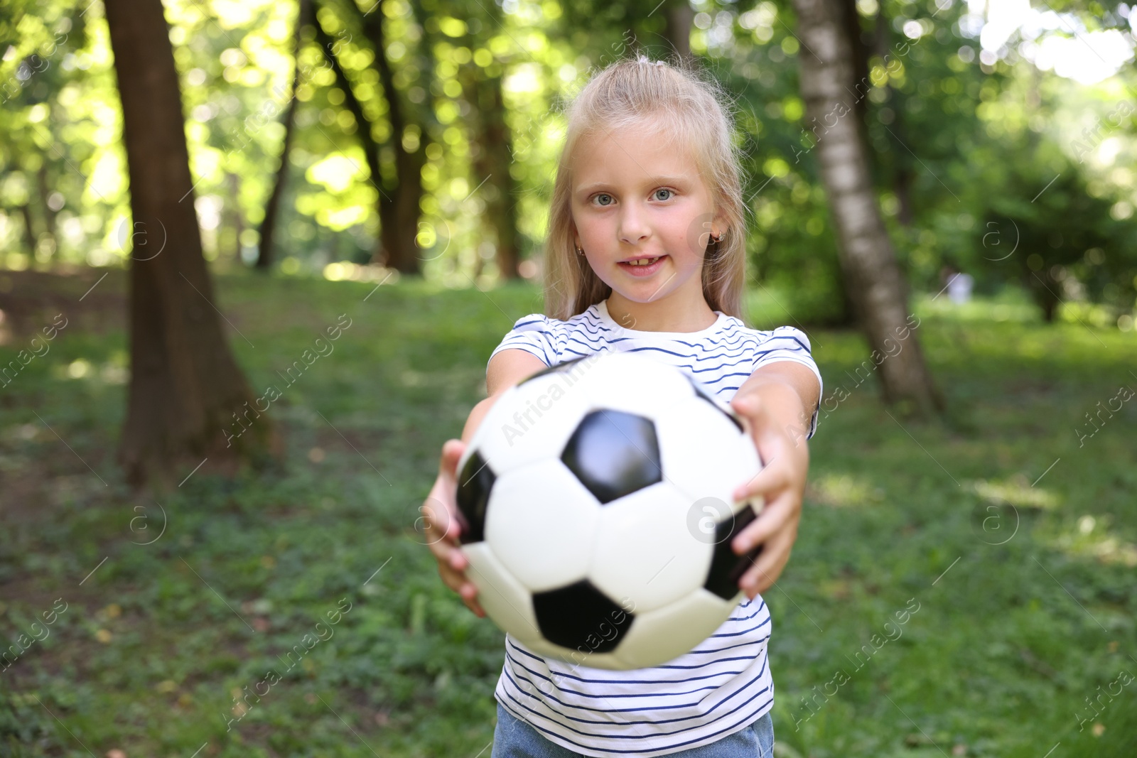 Photo of Cute little girl with soccer ball in park, space for text