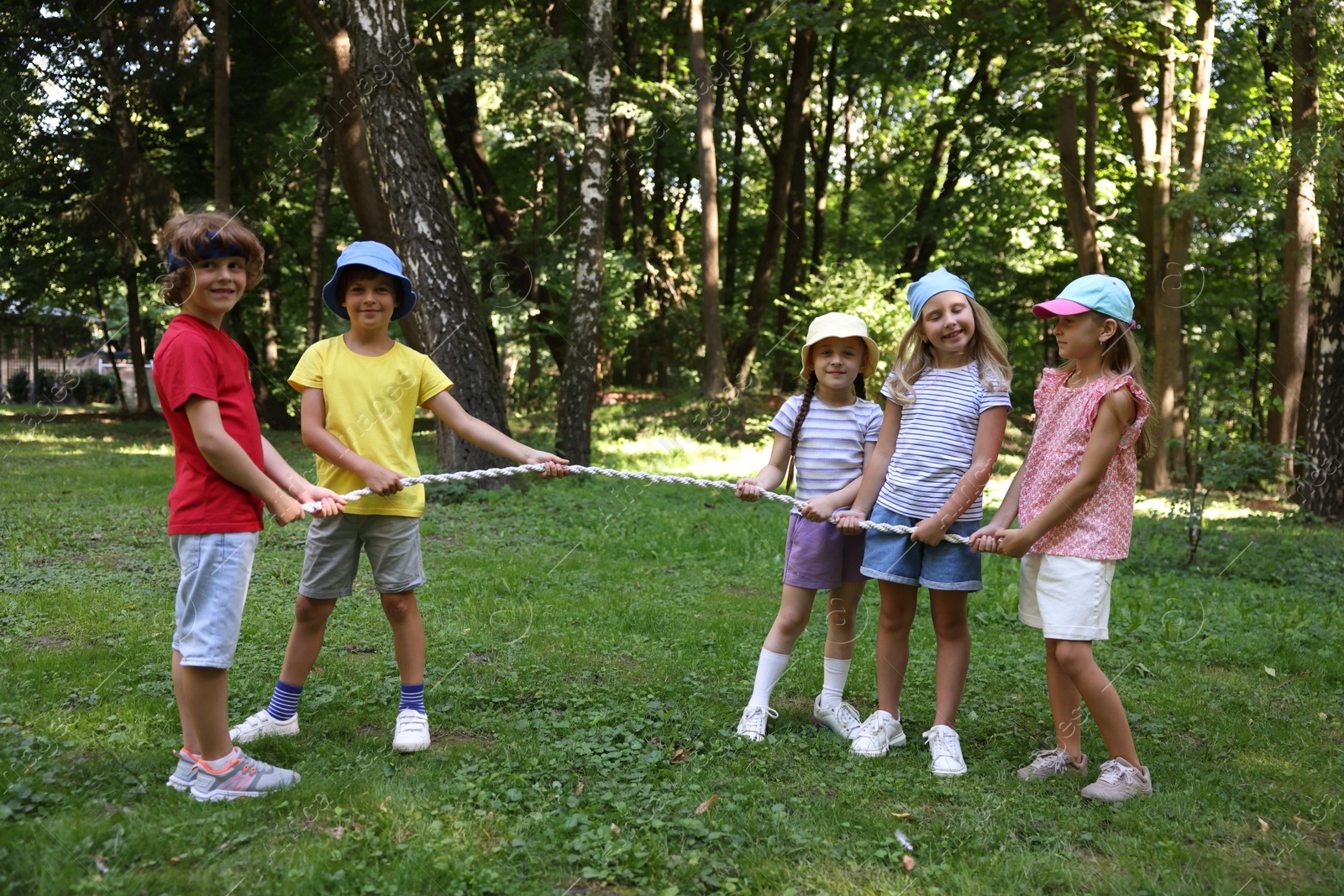 Photo of Cute little kids playing tug of war in park