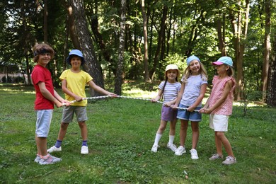 Photo of Cute little kids playing tug of war in park