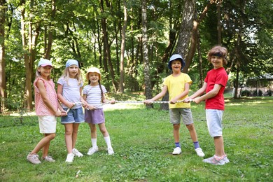 Photo of Cute little kids playing tug of war in park