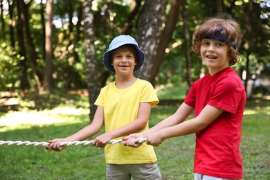 Photo of Cute little kids playing tug of war in park