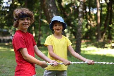 Photo of Cute little kids playing tug of war in park