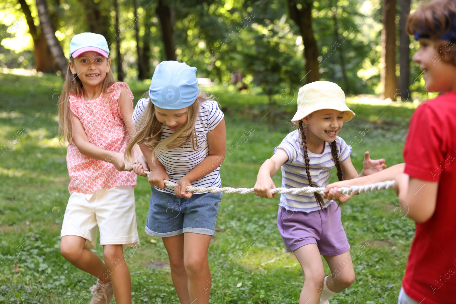 Photo of Cute little kids playing tug of war in park
