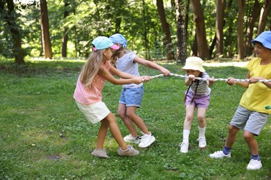 Photo of Cute little kids playing tug of war in park