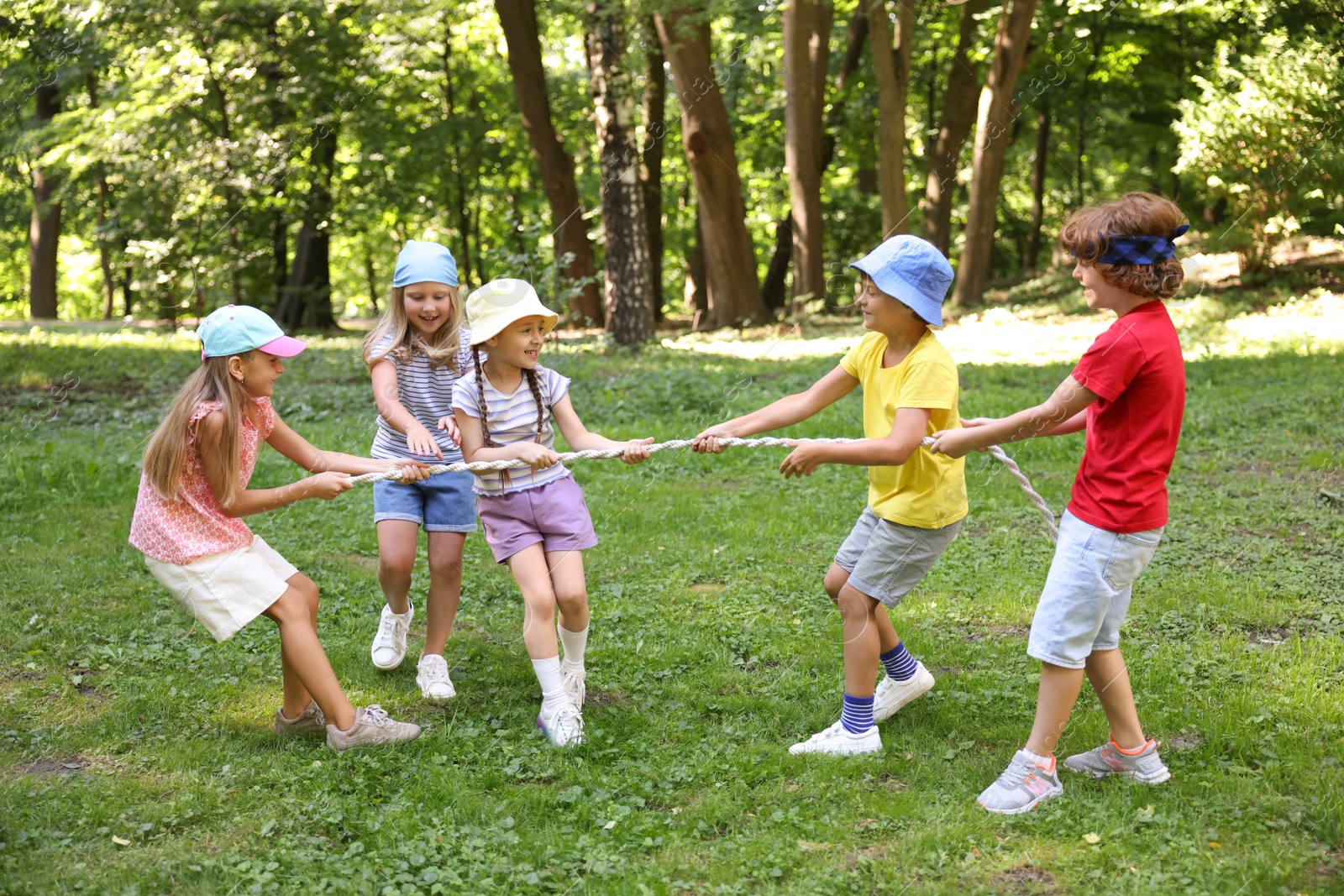 Photo of Cute little kids playing tug of war in park