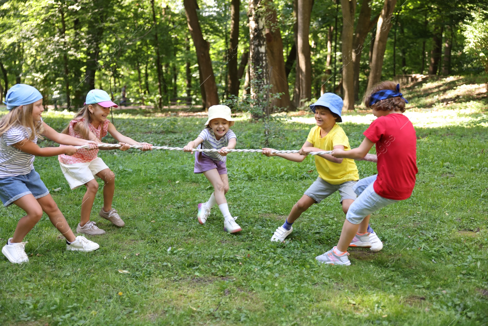 Photo of Cute little kids playing tug of war in park