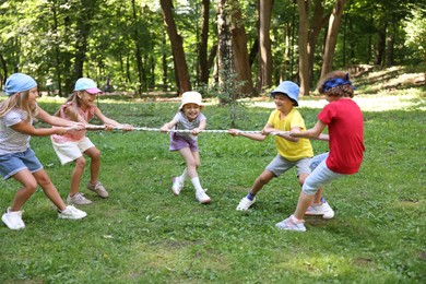 Photo of Cute little kids playing tug of war in park