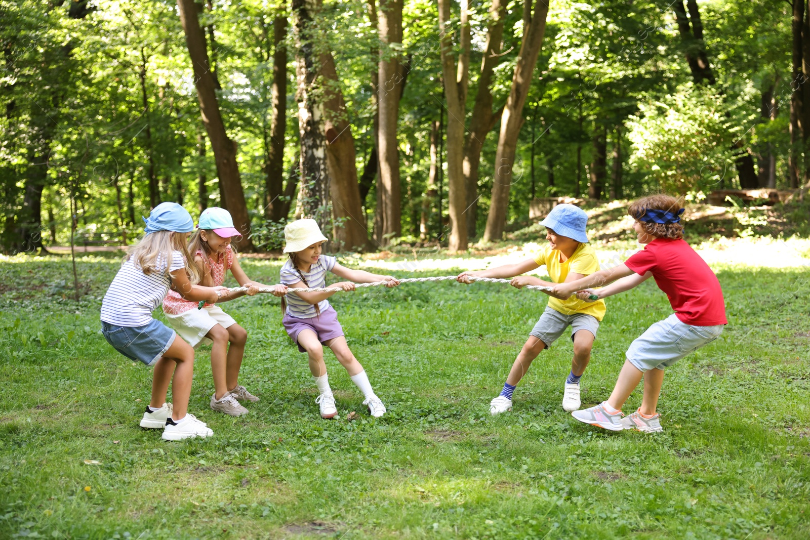 Photo of Cute little kids playing tug of war in park
