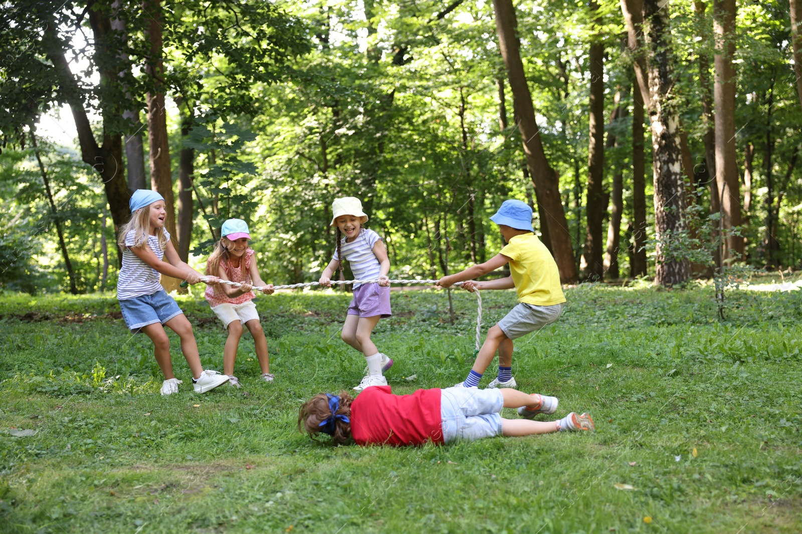 Photo of Cute little kids playing tug of war in park