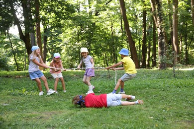 Photo of Cute little kids playing tug of war in park