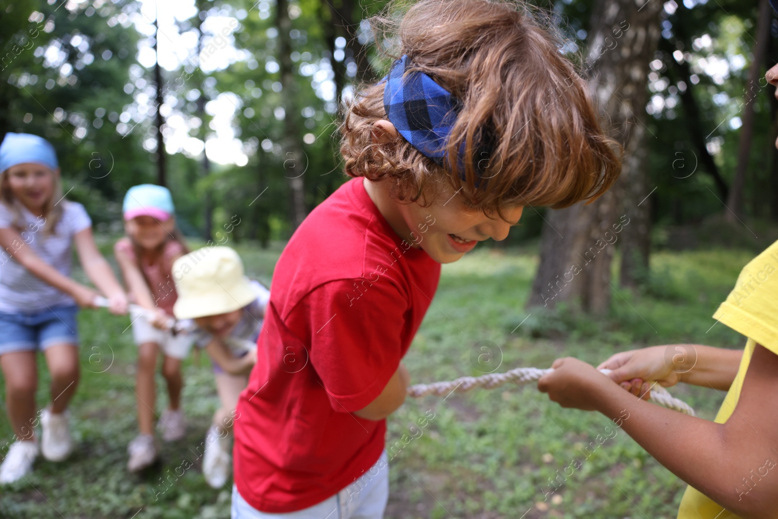 Photo of Cute little kids playing tug of war in park, selective focus