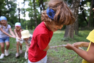 Photo of Cute little kids playing tug of war in park, selective focus