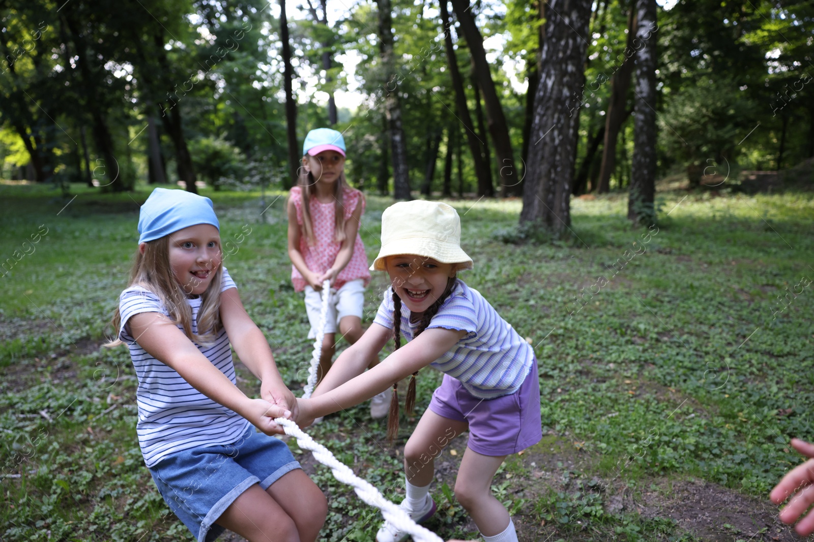 Photo of Cute little kids playing tug of war in park