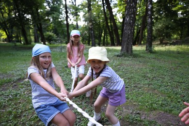 Photo of Cute little kids playing tug of war in park