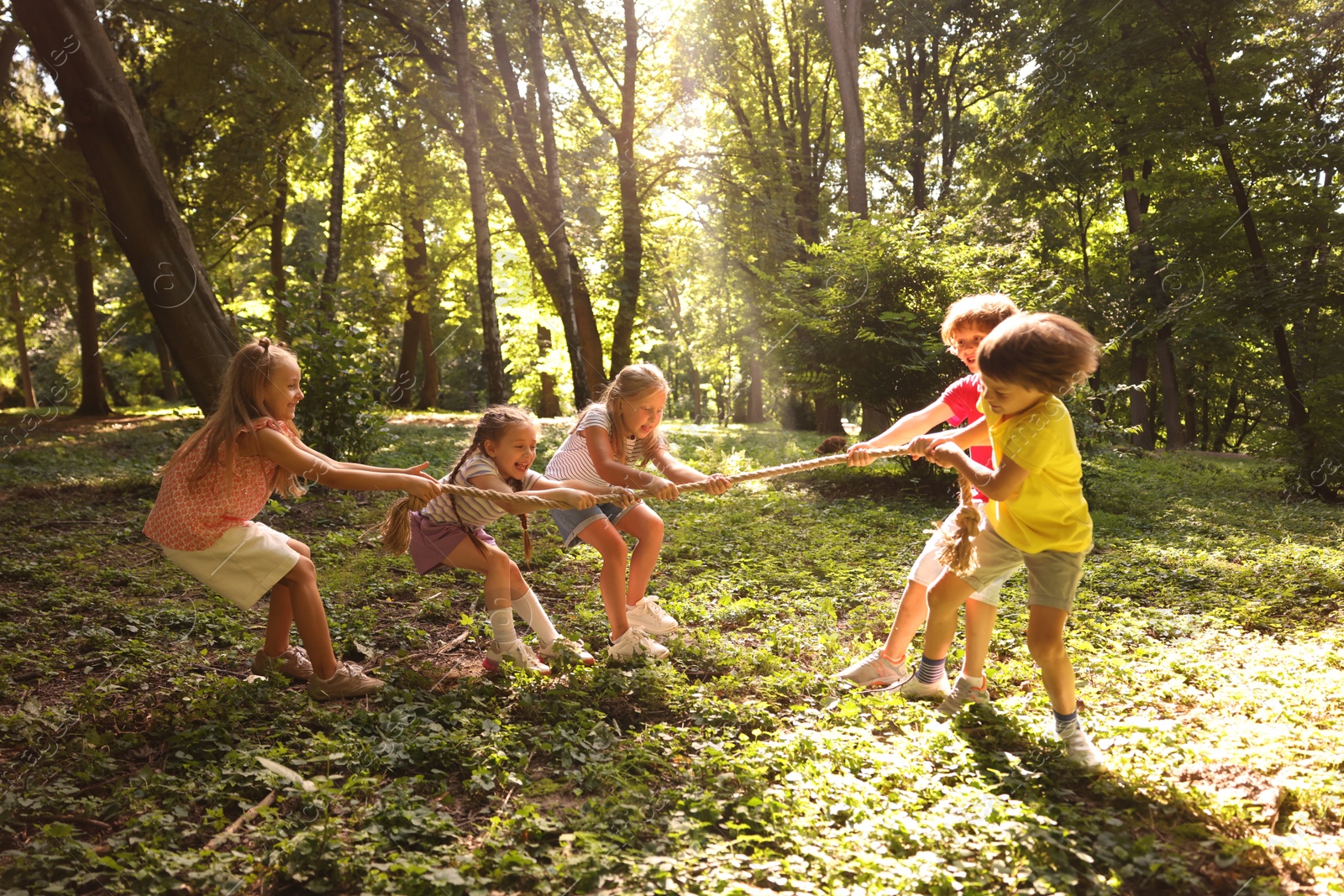 Photo of Cute little kids playing tug of war in park