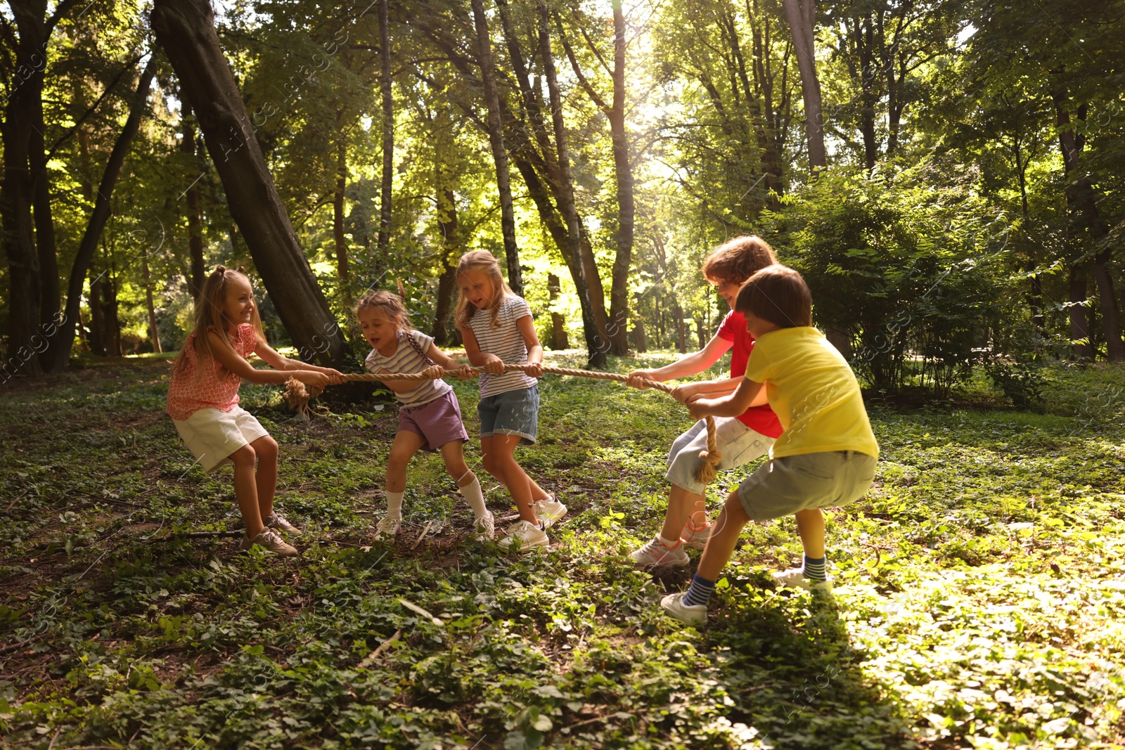 Photo of Cute little kids playing tug of war in park