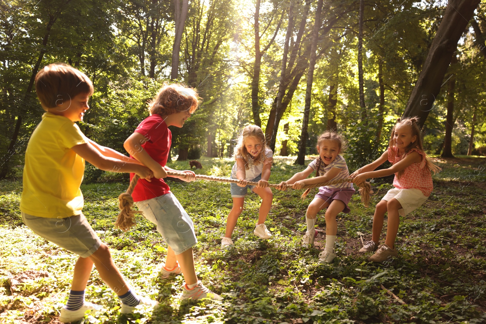 Photo of Cute little kids playing tug of war in park