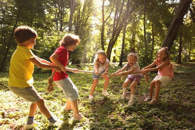 Photo of Cute little kids playing tug of war in park