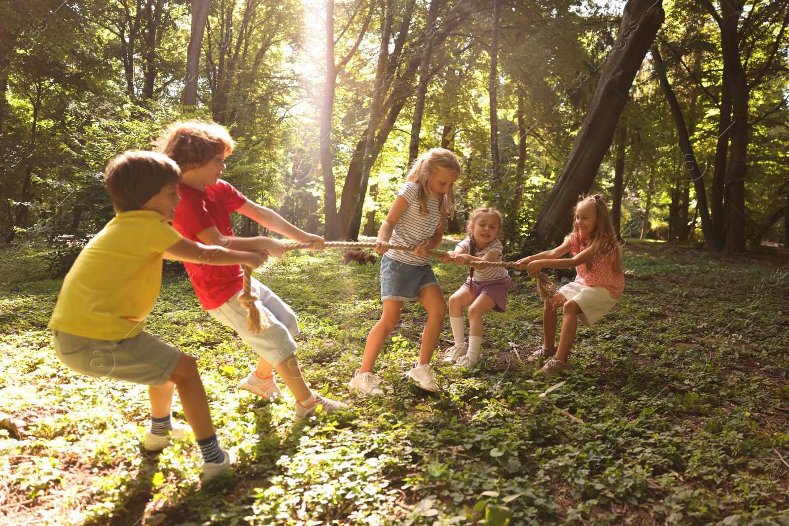 Photo of Cute little kids playing tug of war in park