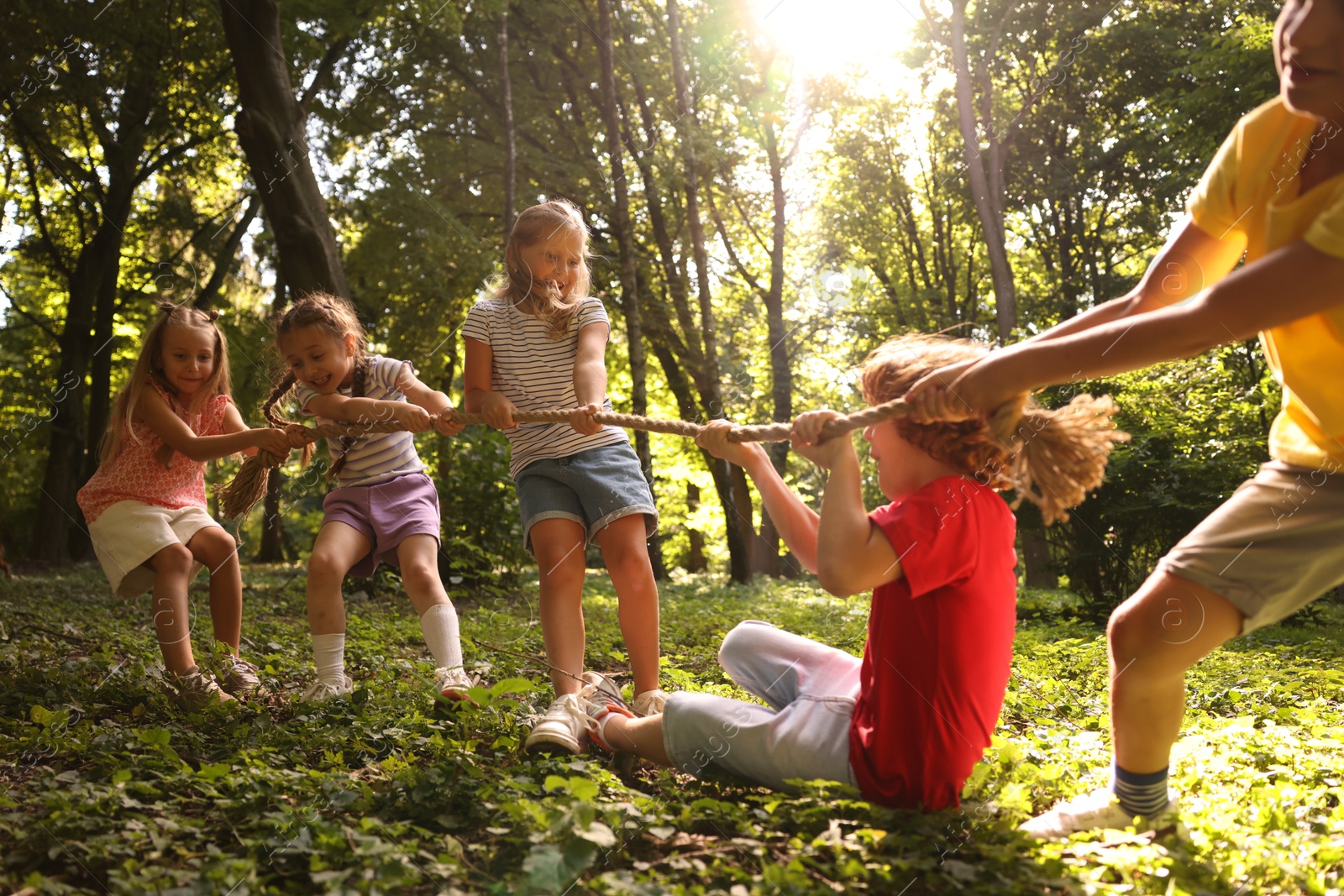 Photo of Cute little kids playing tug of war in park
