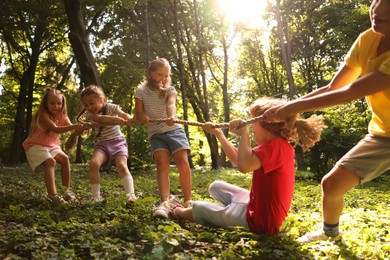 Photo of Cute little kids playing tug of war in park