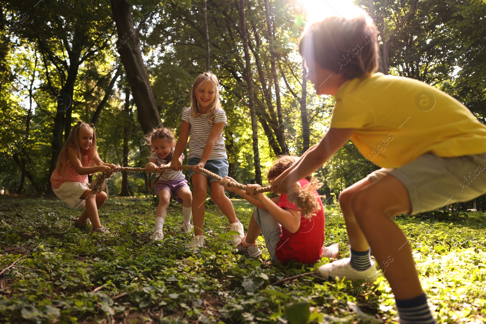 Photo of Cute little kids playing tug of war in park