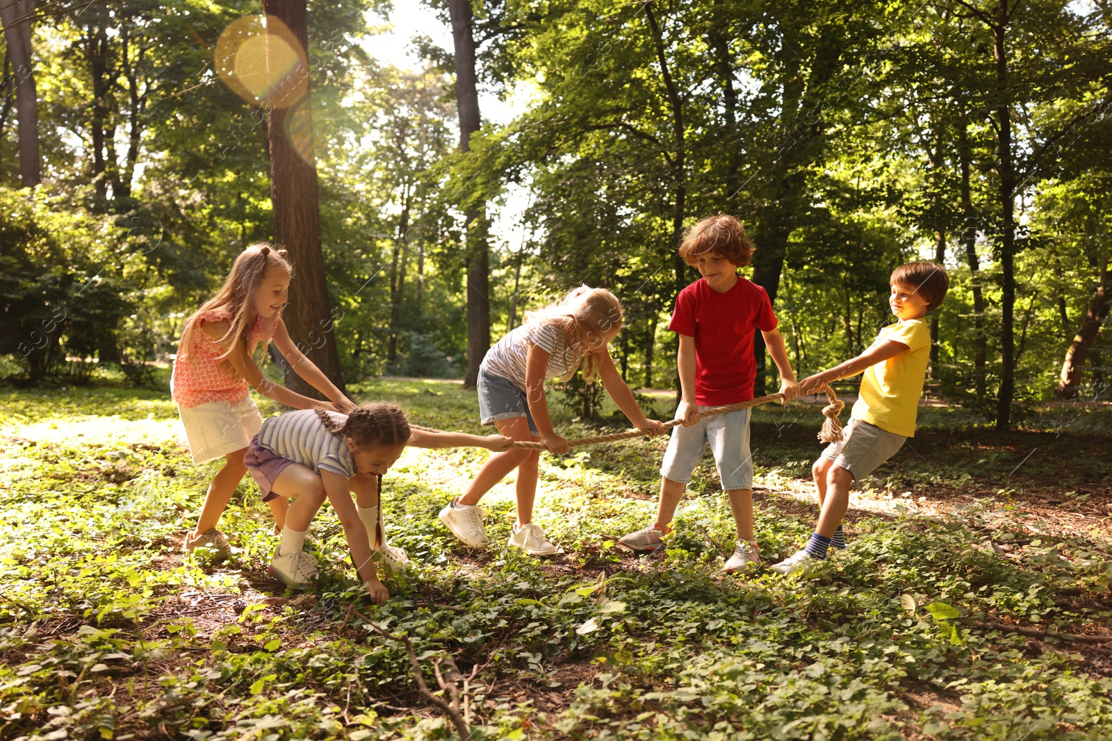 Photo of Cute little kids playing tug of war in park