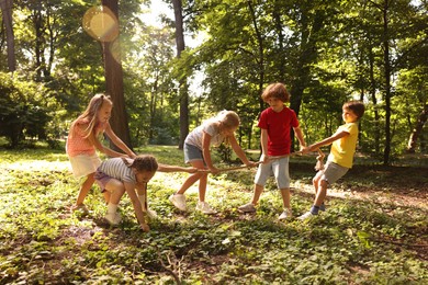 Photo of Cute little kids playing tug of war in park