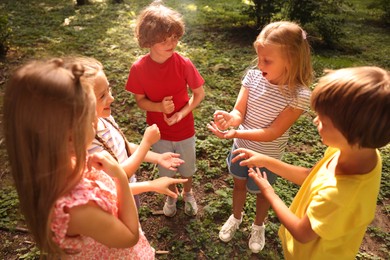 Photo of Cute little kids playing rock, paper and scissors in park, above view