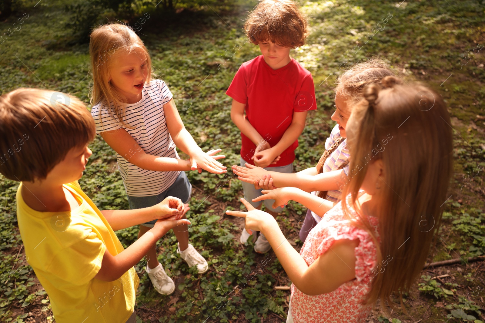 Photo of Cute little kids playing rock, paper and scissors in park, above view