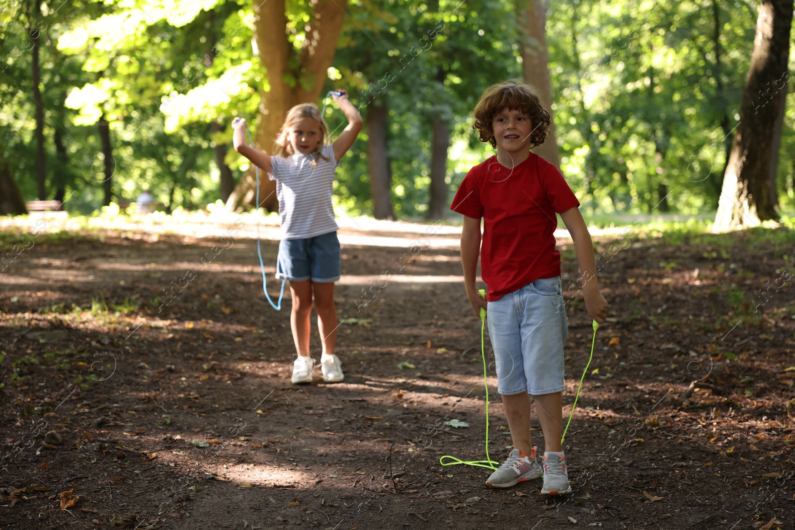 Photo of Cute little kids with jump ropes in park