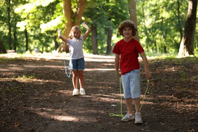 Photo of Cute little kids with jump ropes in park