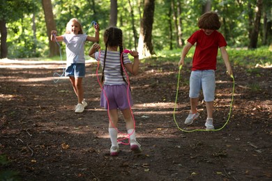 Photo of Cute little kids with jump ropes in park