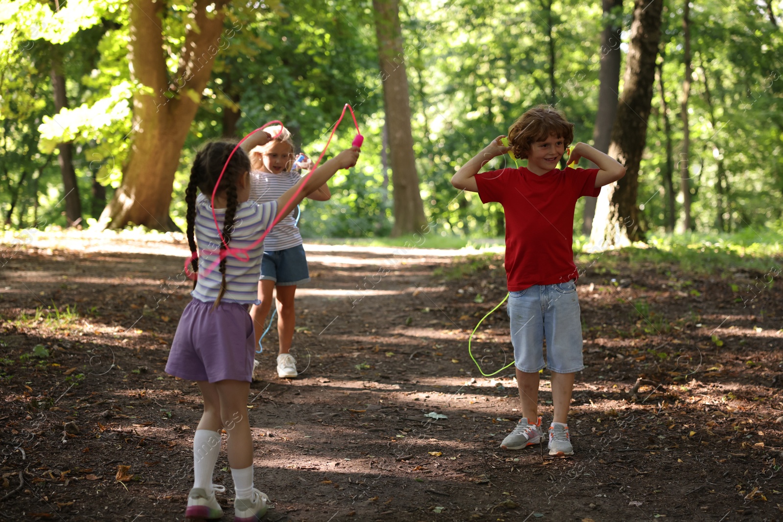 Photo of Cute little kids with jump ropes in park
