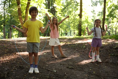 Photo of Cute little kids with jump ropes in park
