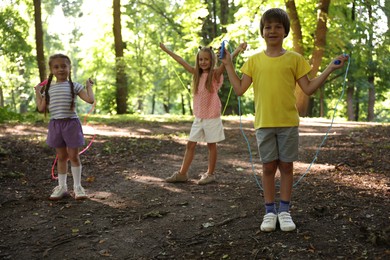 Photo of Cute little kids with jump ropes in park