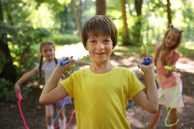 Photo of Cute little kids with jump ropes in park, selective focus